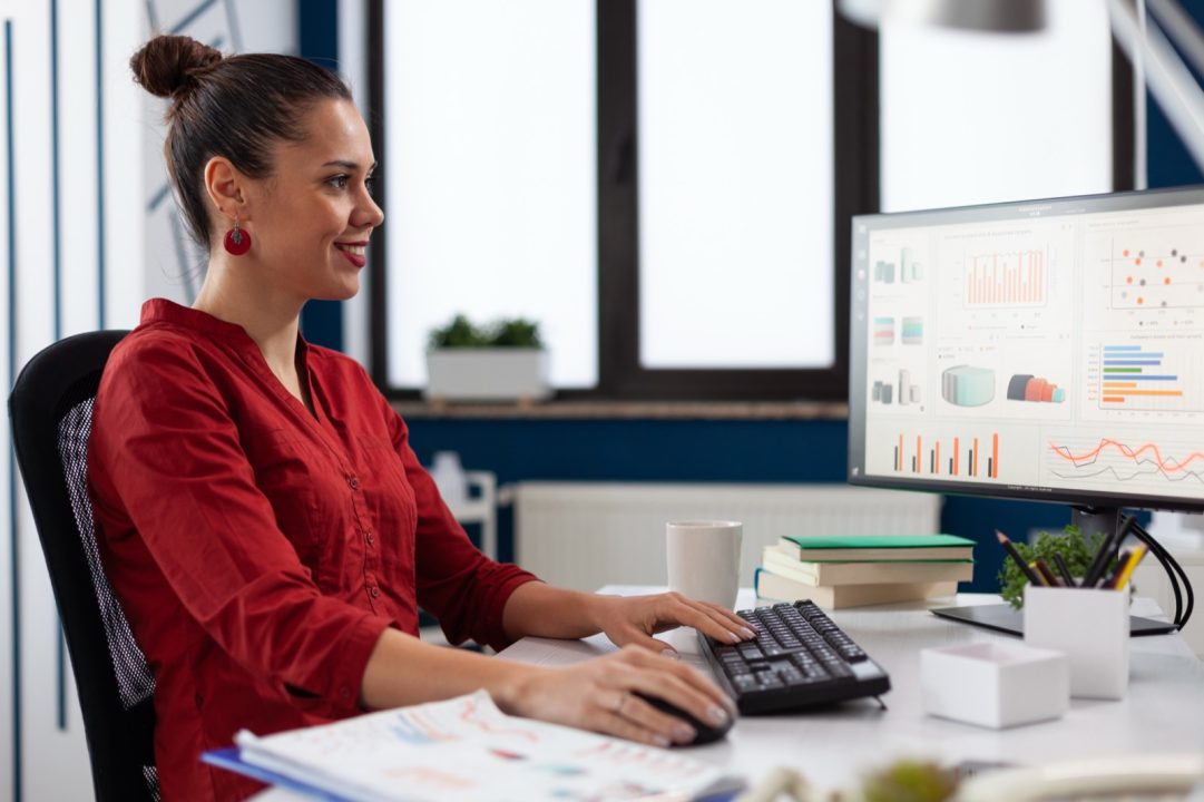 Jeune diplome analysant des graphiques financiers sur ordinateur