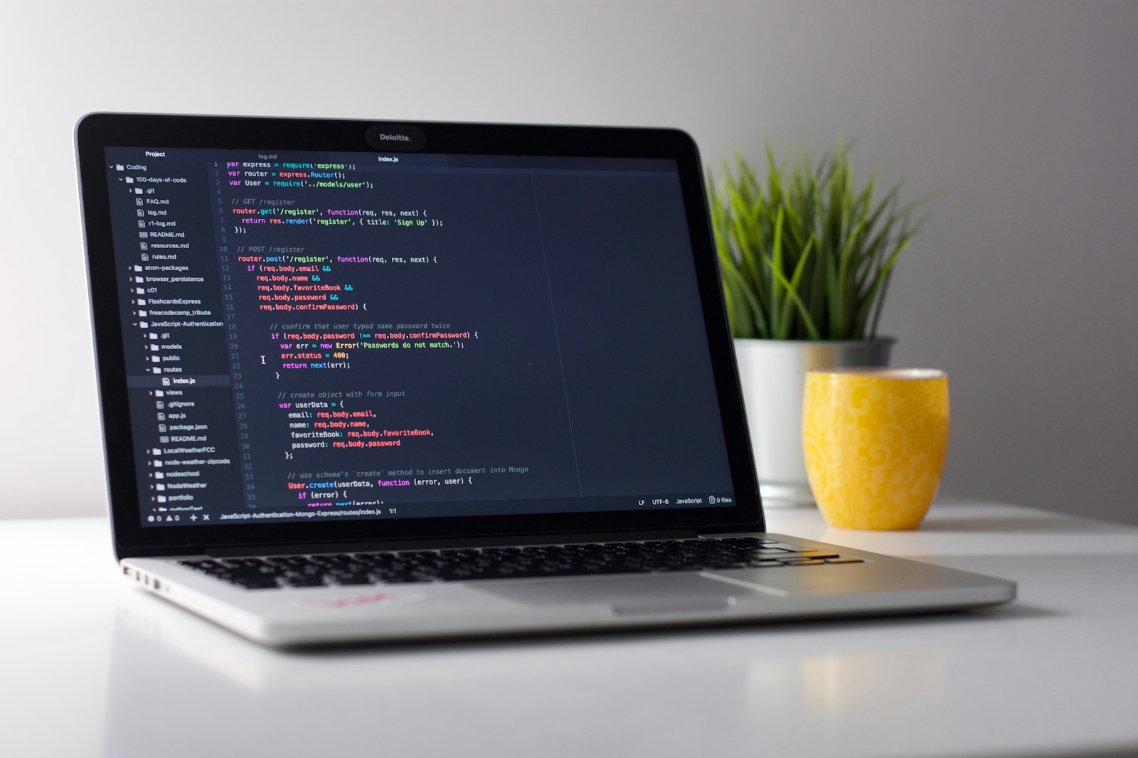 Développeuse assise devant deux écrans affichant du code et la maquette d'une application mobile, dans un bureau partagé avec son équipe